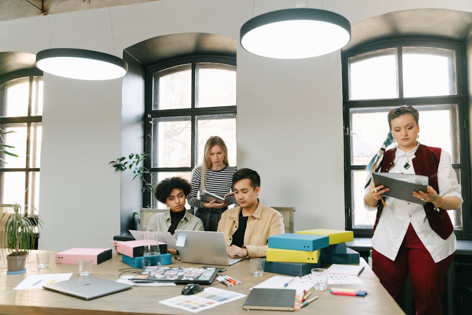 Diverse team brainstorming in a modern office setting with laptops and documents.